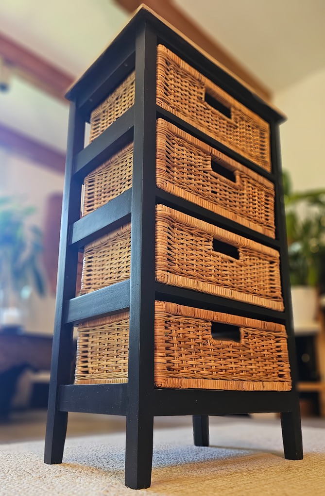 Mueble renovado de segunda mano con cestas de mimbre y estructura negra, ideal para decoración económica y sostenible.