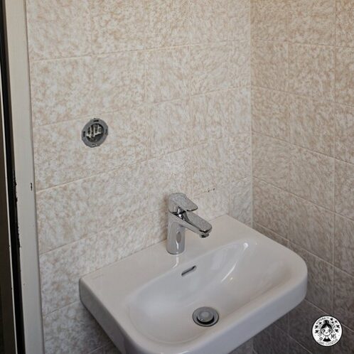 Lavabo en aseo pequeño con azulejos antiguos antes de la renovación