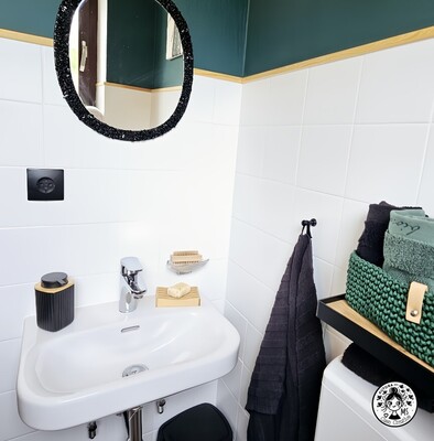 Lavabo con espejo DIY y decoración en baño pequeño reformado en blanco, negro y verde