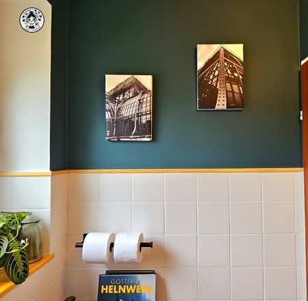 Pared verde con cuadros en blanco y negro y soporte doble de papel higiénico en aseo reformado