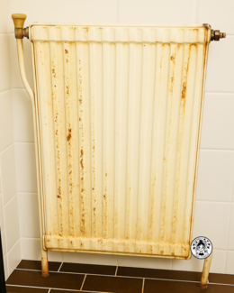 Radiador oxidado en aseo antiguo antes de reforma decorativa.