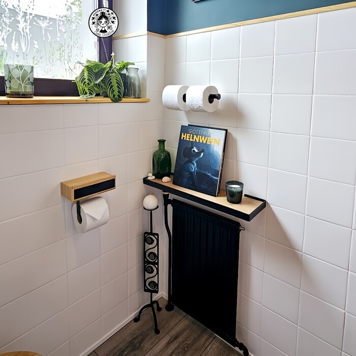 Vista decorativa de aseo reformado con radiador negro, estante de madera, libro artístico y plantas naturales