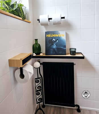 Detalle de estantería en aseo reformado con libro de arte, botella de cristal, vela y radiador negro