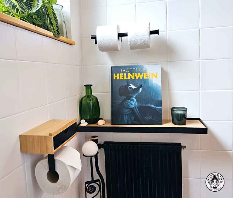 Detalle de estantería en aseo reformado con libro de arte, botella de cristal, vela y radiador negro