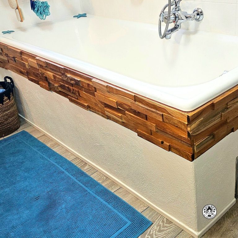 Bañera con enlucido pintado a la cal blanca y paneles de madera barnizados en una reforma de baño.