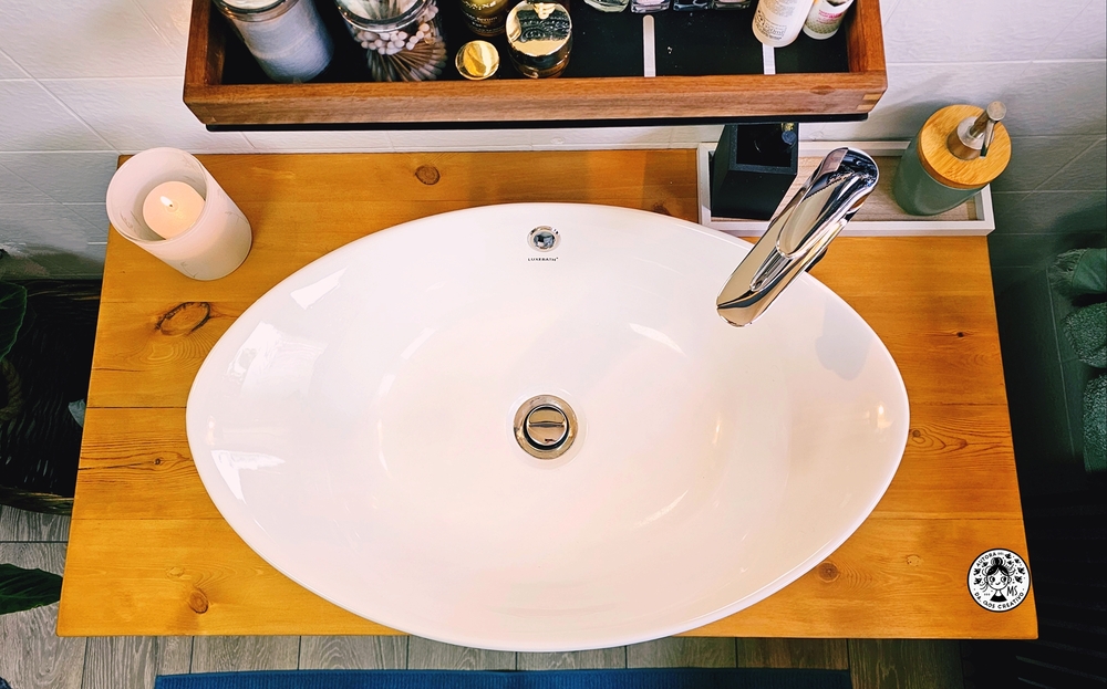 Lavabo ovalado sobre encimera de madera natural, integrado en un mueble renovado de baño